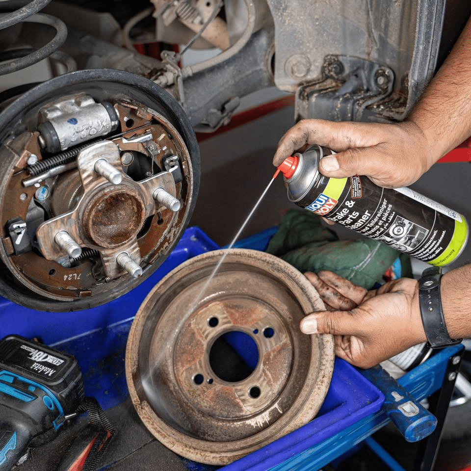 A person cleaning brake rotors with a household item