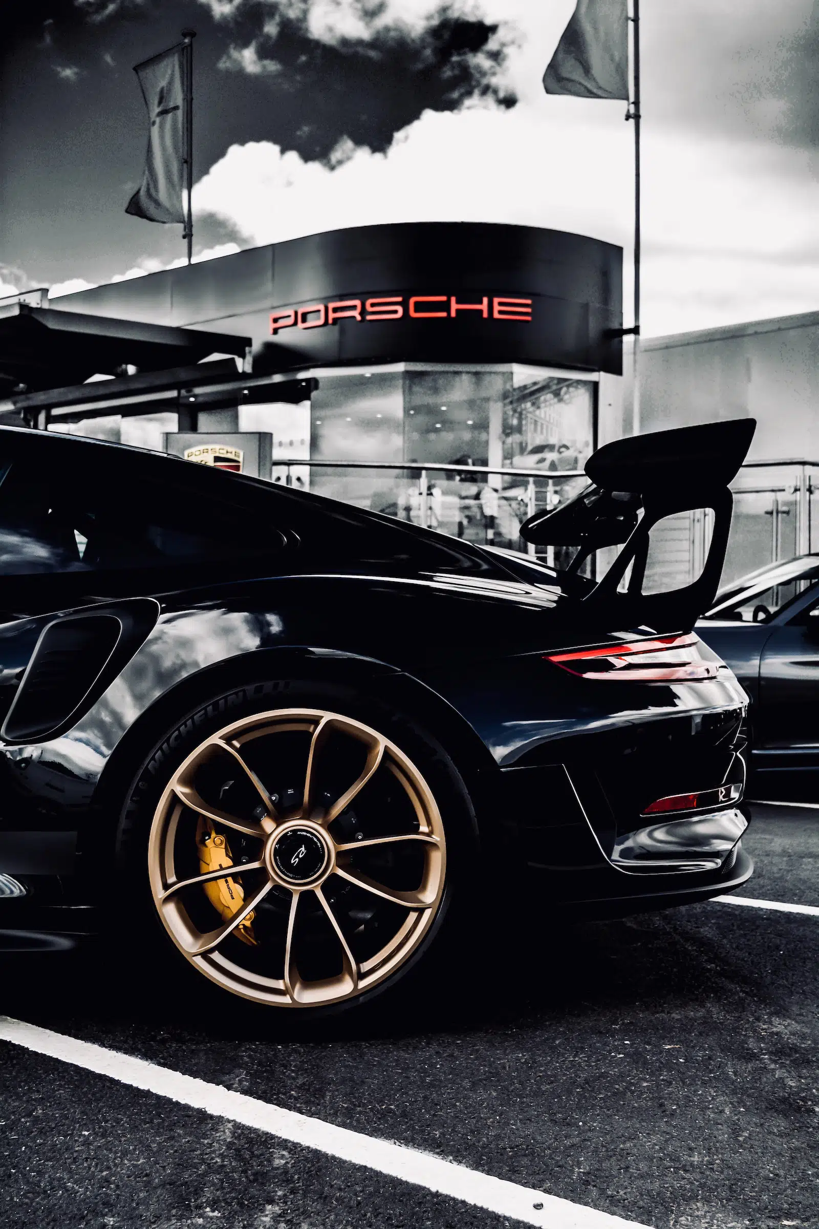 Black Porsche 911 parked outside a Porsche dealership