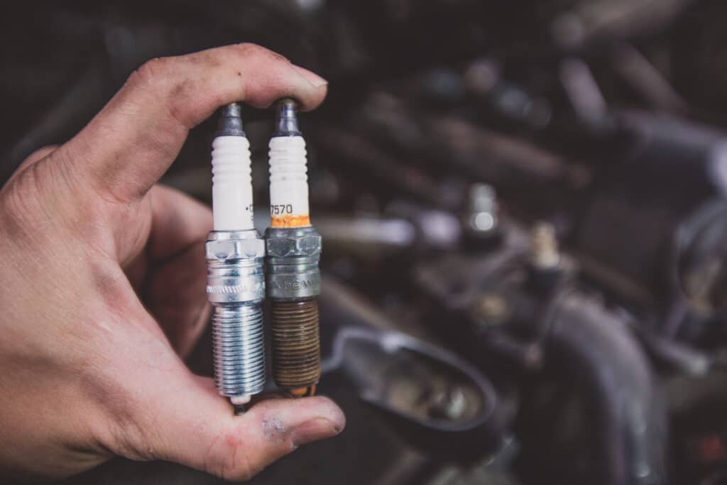 hand holding an old and new spark plug