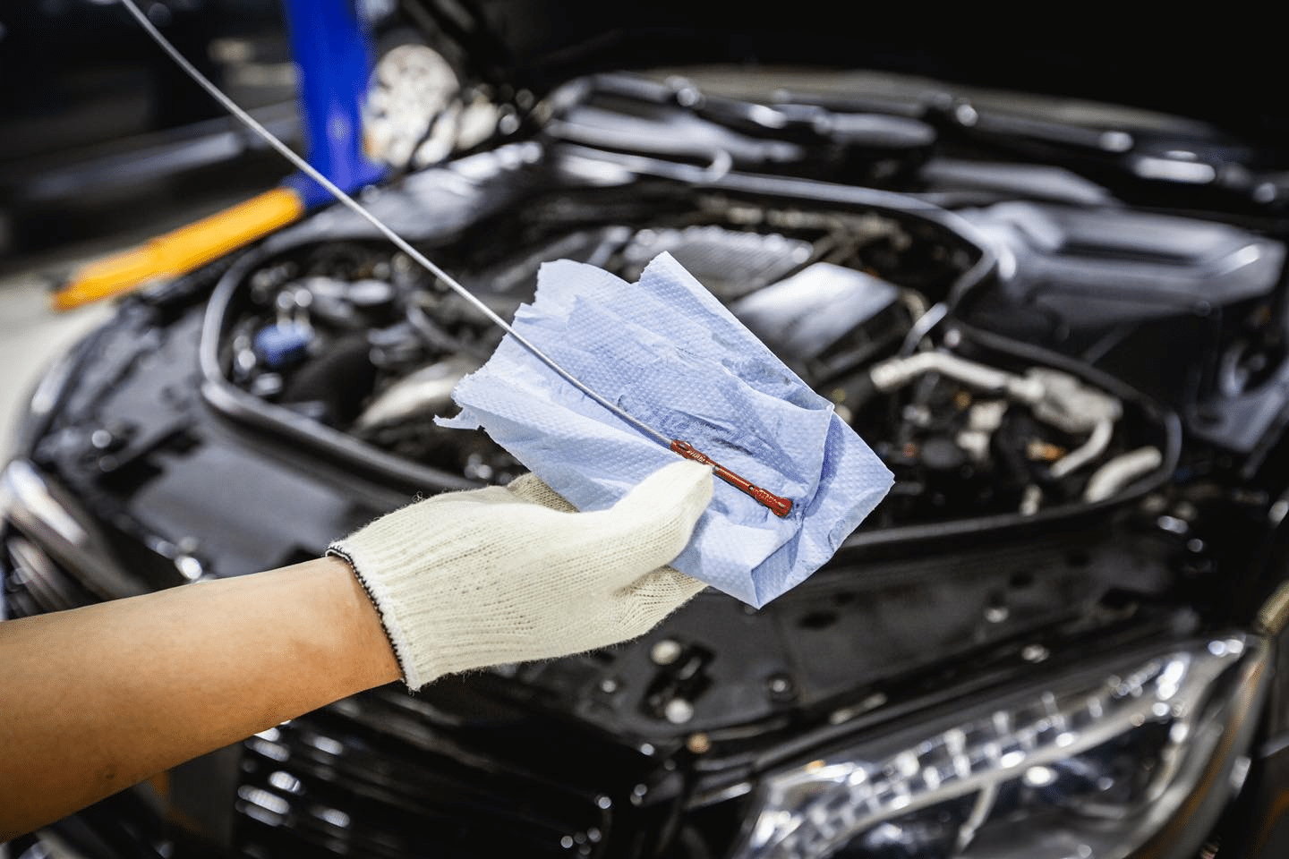 An image showing a car undergoing MOT checks with a mechanic inspecting the vehicle.
